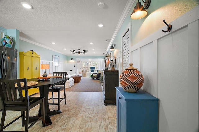 dining area featuring recessed lighting, light wood-style floors, ornamental molding, and a textured ceiling
