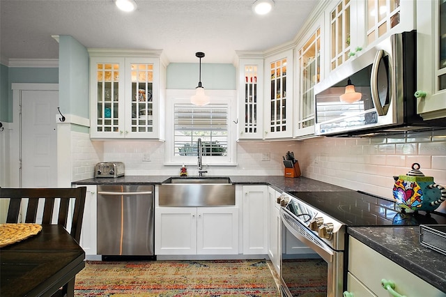 kitchen with a sink, stainless steel appliances, crown molding, decorative light fixtures, and backsplash