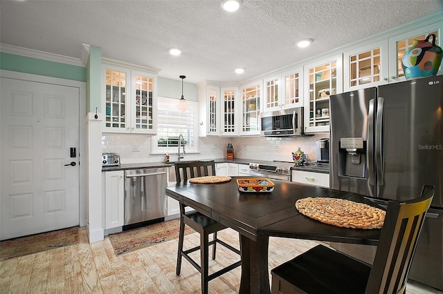 kitchen featuring dark countertops, appliances with stainless steel finishes, white cabinetry, and light wood-type flooring