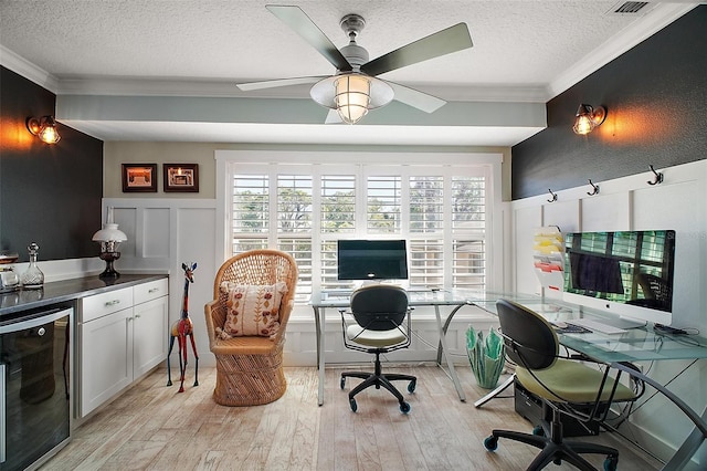 office area with light wood finished floors, wine cooler, a textured ceiling, crown molding, and a decorative wall