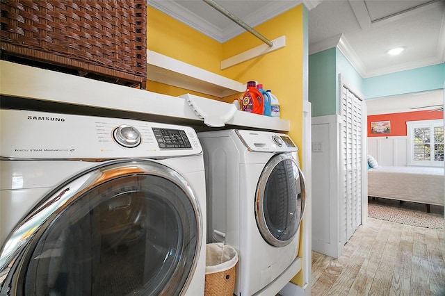clothes washing area with light wood finished floors, washing machine and clothes dryer, attic access, laundry area, and ornamental molding