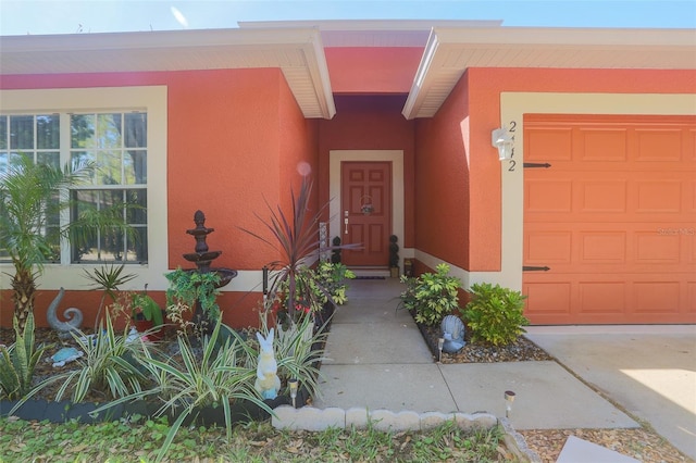 2442 Foxhollow Rd, Tavares, FL 32778 - view of exterior entry featuring stucco siding and an attached garage