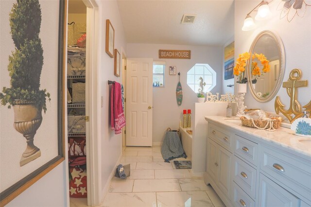 2442 Foxhollow Rd, Tavares, FL 32778 - full bathroom with visible vents, marble finish floor, vanity, a garden tub, and a spacious closet