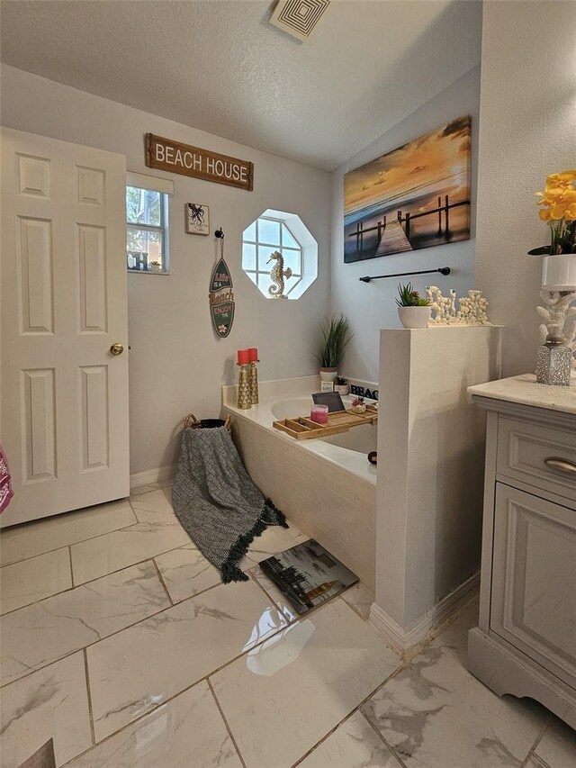 2442 Foxhollow Rd, Tavares, FL 32778 - bathroom with baseboards, a textured ceiling, marble finish floor, visible vents, and a bath