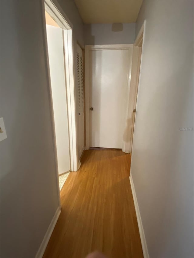 hallway featuring baseboards and light wood-style floors