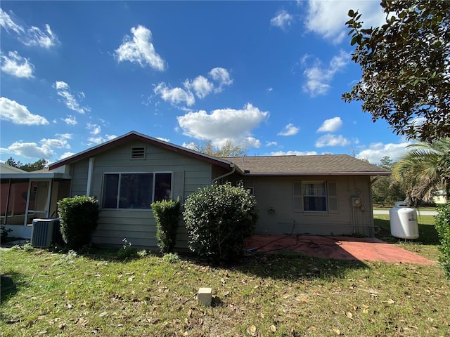 rear view of property featuring a sunroom, central AC, a yard, and a patio