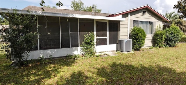 back of house featuring central air condition unit, a lawn, and a sunroom