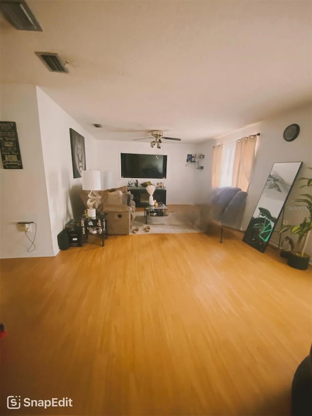 unfurnished living room with visible vents, a ceiling fan, and wood finished floors