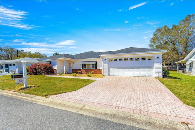 ranch-style home featuring a front lawn, decorative driveway, and an attached garage