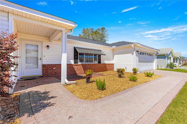 exterior space with brick siding, an attached garage, and driveway