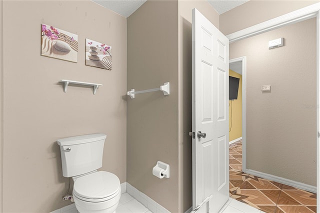 bathroom featuring tile patterned floors, toilet, and baseboards