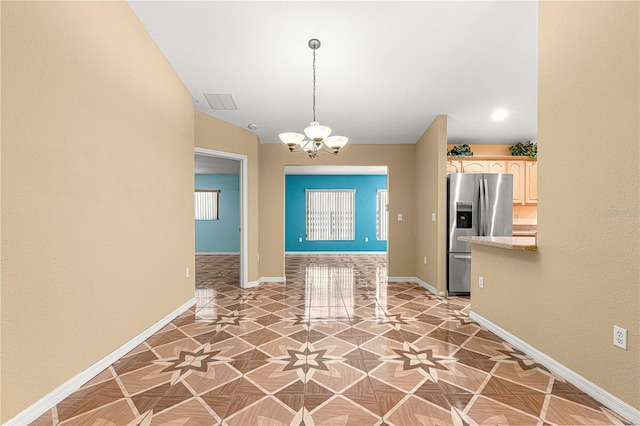 kitchen featuring a notable chandelier, stainless steel fridge, light countertops, and baseboards