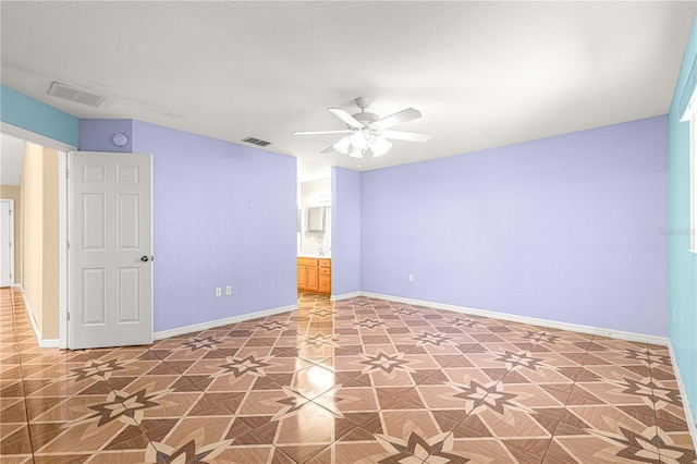 unfurnished room with baseboards, visible vents, and a textured ceiling