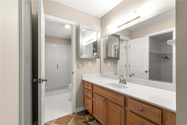 bathroom featuring vanity, a shower stall, and toilet