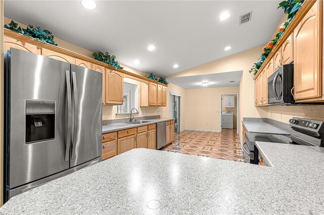 kitchen with visible vents, lofted ceiling, appliances with stainless steel finishes, washer / clothes dryer, and a sink