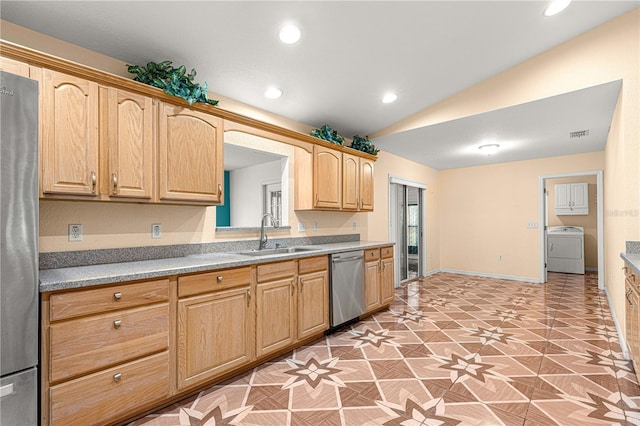 kitchen with light brown cabinetry, lofted ceiling, stainless steel appliances, washer / clothes dryer, and a sink