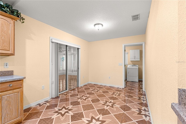 interior space with visible vents, baseboards, a textured ceiling, and washer / dryer