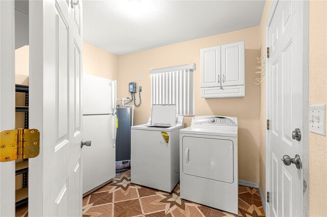 washroom featuring washer and dryer, cabinet space, and a textured ceiling