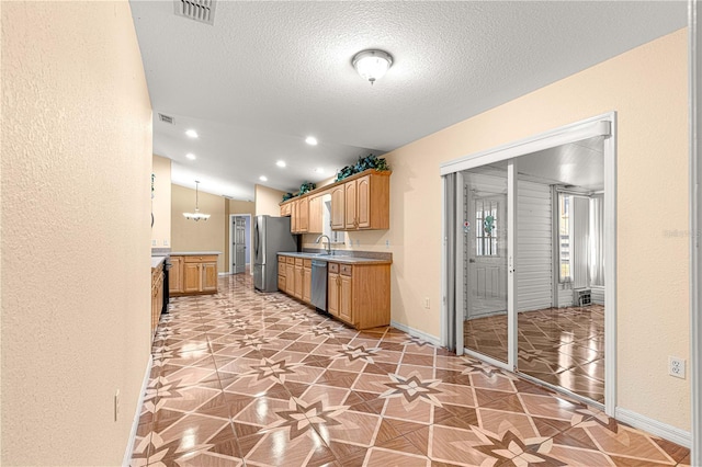 kitchen with visible vents, baseboards, vaulted ceiling, appliances with stainless steel finishes, and a textured ceiling