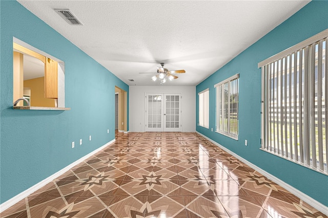empty room with baseboards, plenty of natural light, a textured ceiling, and ceiling fan