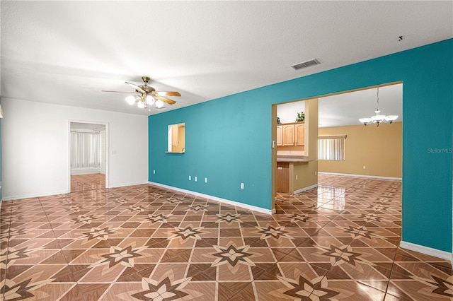 spare room featuring visible vents, ceiling fan with notable chandelier, a textured ceiling, and baseboards
