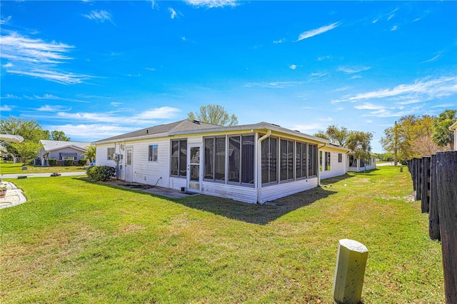 back of house with a lawn, fence, and a sunroom