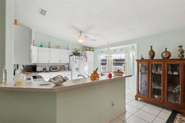 kitchen featuring a peninsula, light tile patterned floors, white appliances, visible vents, and ceiling fan
