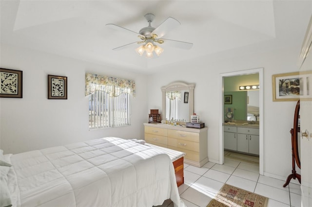 bedroom with baseboards, connected bathroom, ceiling fan, a raised ceiling, and light tile patterned floors