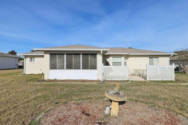 back of house with a lawn, stucco siding, a sunroom, and a patio
