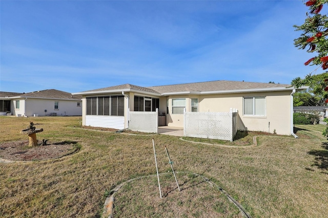 back of property with stucco siding, a sunroom, roof with shingles, and a yard