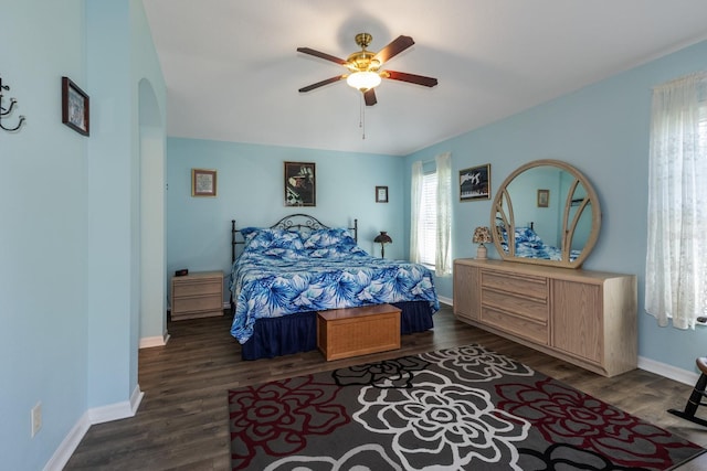 bedroom with a ceiling fan, arched walkways, baseboards, and wood finished floors