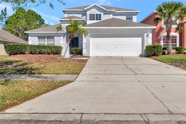 traditional home featuring stucco siding, an attached garage, concrete driveway, and a shingled roof