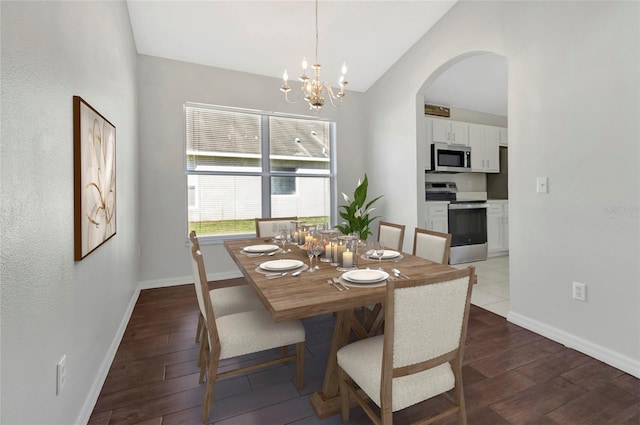 dining area with arched walkways, baseboards, lofted ceiling, and wood finished floors
