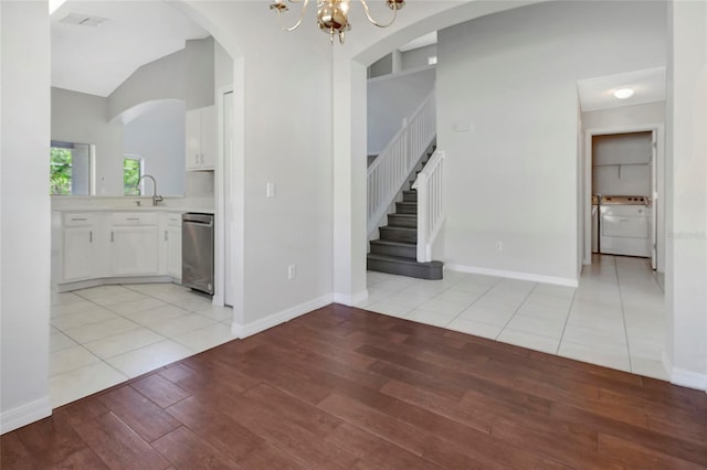 unfurnished dining area featuring baseboards, an inviting chandelier, light wood-style flooring, washer / clothes dryer, and stairs