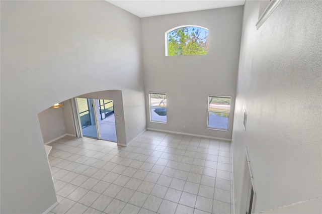 tiled entryway with a high ceiling, plenty of natural light, and baseboards