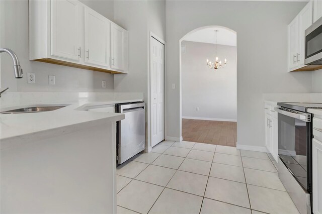 kitchen with light tile patterned floors, a sink, light countertops, white cabinets, and appliances with stainless steel finishes