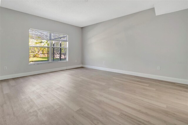 empty room featuring baseboards and light wood-style flooring