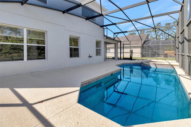 outdoor pool featuring glass enclosure and a patio