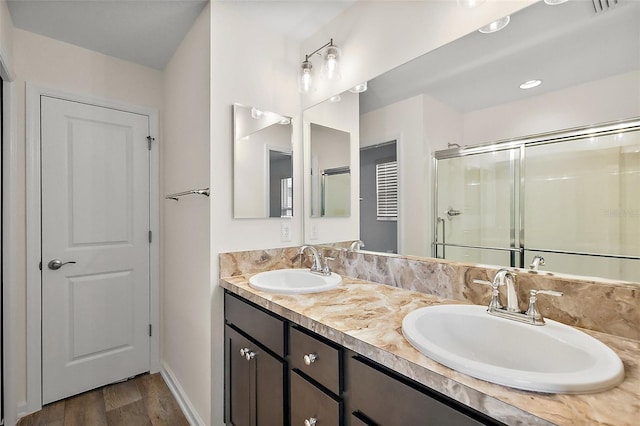 3557 Cochran St, The Villages, FL 32163 - bathroom featuring a stall shower, wood finished floors, double vanity, and a sink