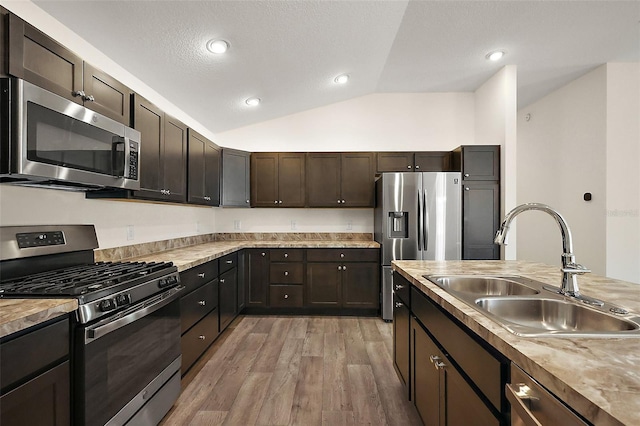 3557 Cochran St, The Villages, FL 32163 - kitchen with dark brown cabinets, vaulted ceiling, a sink, light wood-style flooring, and appliances with stainless steel finishes