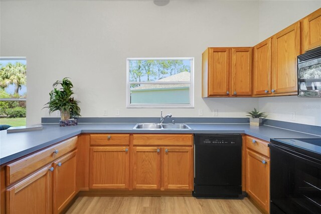 2433 Tamarindo Dr, The Villages, FL 32162 - kitchen featuring a peninsula, light wood finished floors, a sink, black appliances, and brown cabinetry