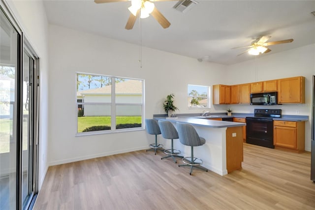 2433 Tamarindo Dr, The Villages, FL 32162 - kitchen with visible vents, black appliances, a peninsula, and a ceiling fan
