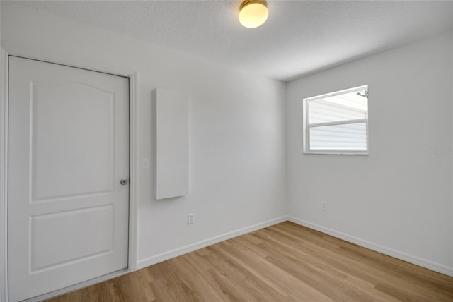 2433 Tamarindo Dr, The Villages, FL 32162 - empty room featuring baseboards, light wood-style floors, and a textured ceiling