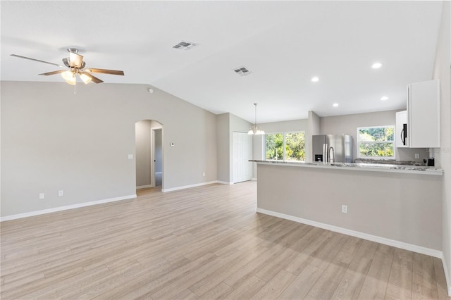 unfurnished living room featuring visible vents, ceiling fan, light wood-type flooring, vaulted ceiling, and arched walkways