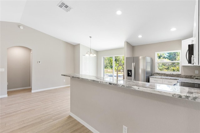 kitchen with light wood-type flooring, visible vents, lofted ceiling, stainless steel refrigerator with ice dispenser, and light stone countertops