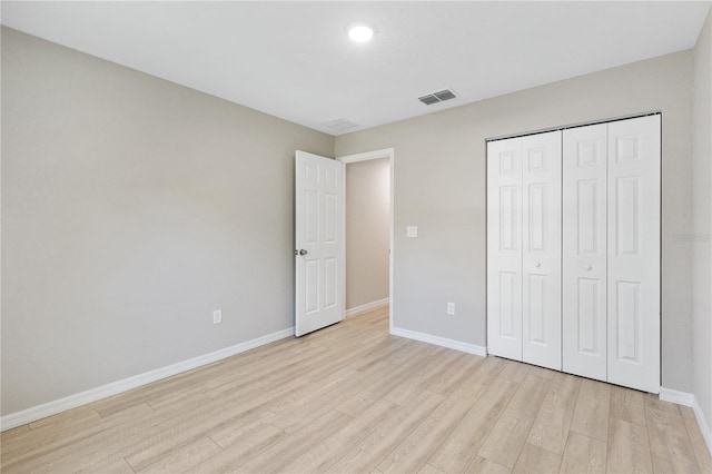 unfurnished bedroom with a closet, visible vents, baseboards, and light wood-style floors