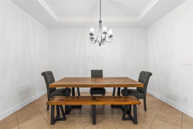 dining space featuring baseboards, a notable chandelier, and a raised ceiling