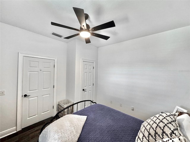 bedroom with visible vents, dark wood-style flooring, and a ceiling fan
