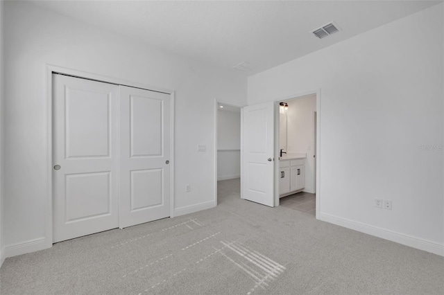 unfurnished bedroom with visible vents, baseboards, a closet, ensuite bathroom, and light colored carpet