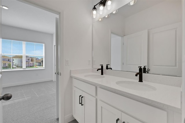 full bath with double vanity, baseboards, and a sink